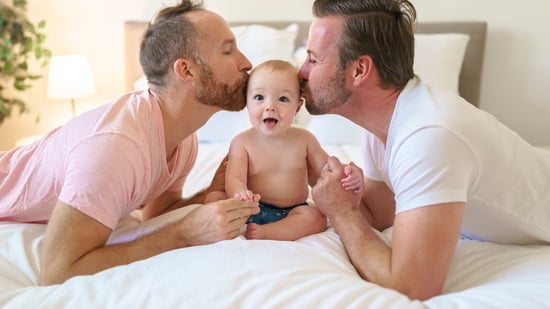 gay couple kissing their smiling baby on the head