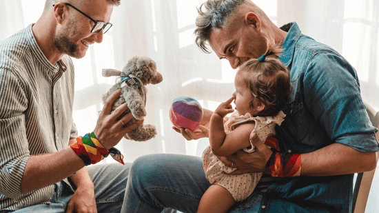 gay couple playing with toddler daughter 