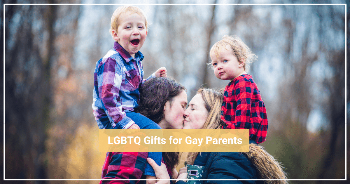 two children sitting on shoulders of lesbian moms kissing with forest in background